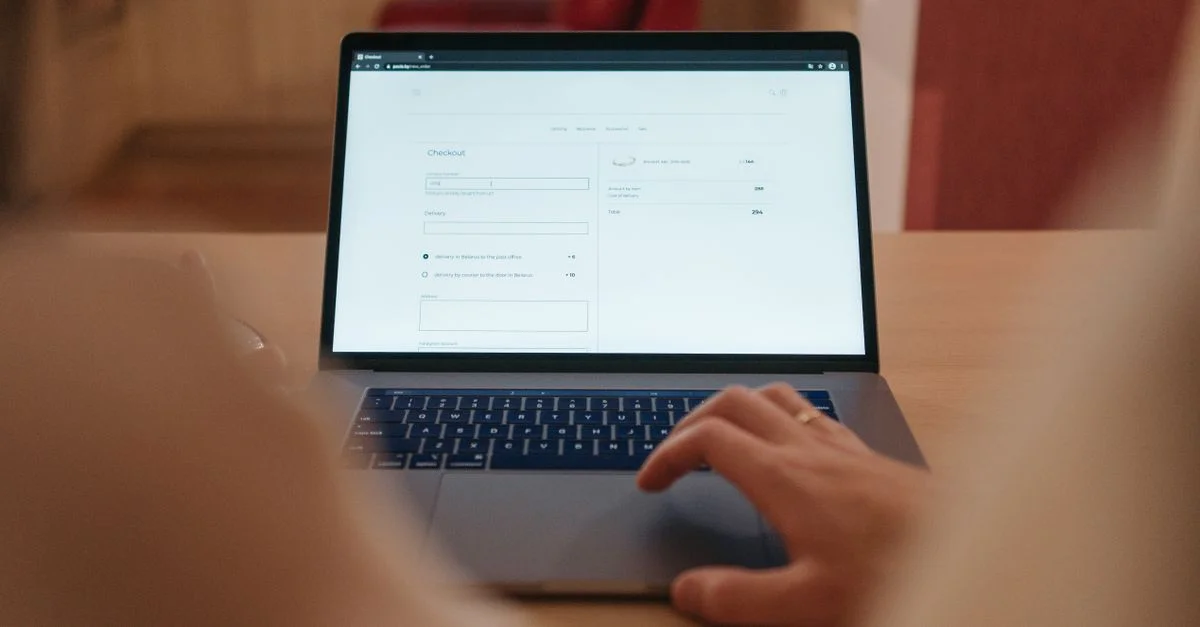 Gros plan sur une personne utilisant le processus de paiement en ligne sur un écran d'ordinateur portable dans un cadre intérieur confortable.