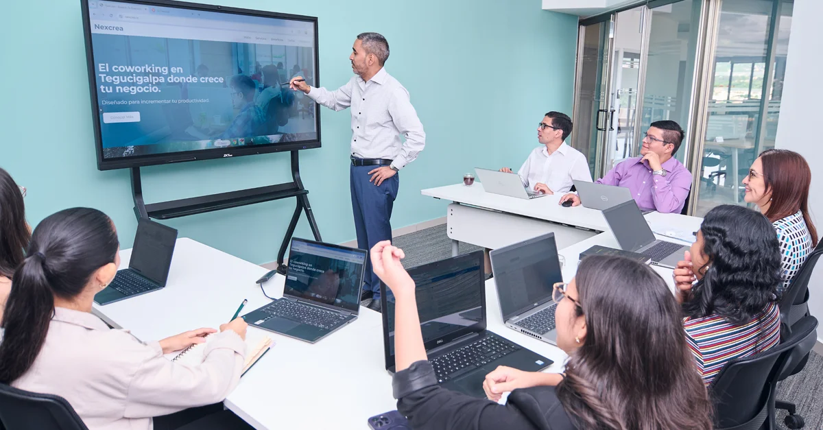 Une équipe de professionnels s'est engagée dans une présentation commerciale avec des ordinateurs portables et un écran de projection.