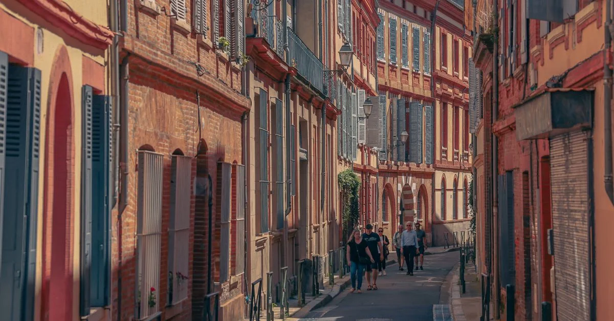 Rue pittoresque de Toulouse présentant une architecture historique et des piétons sous un ciel ensoleillé.