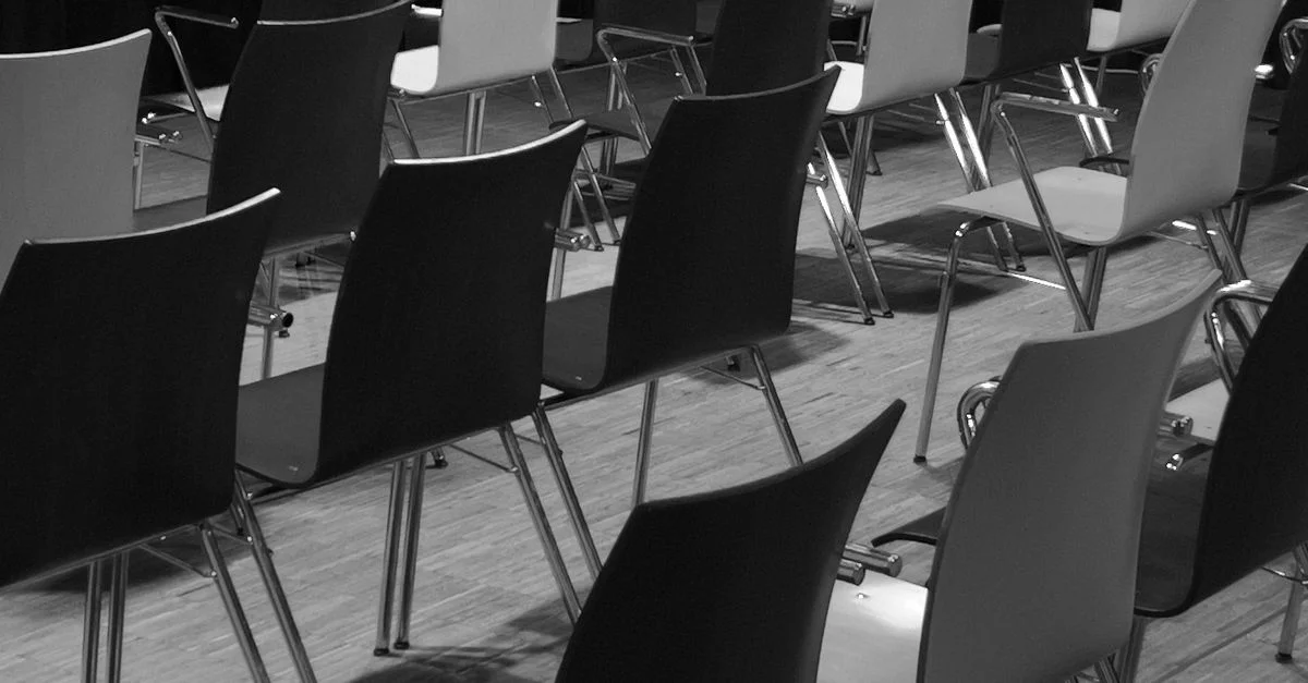 Photo en noir et blanc de chaises vides dans une configuration de salle de conférence.