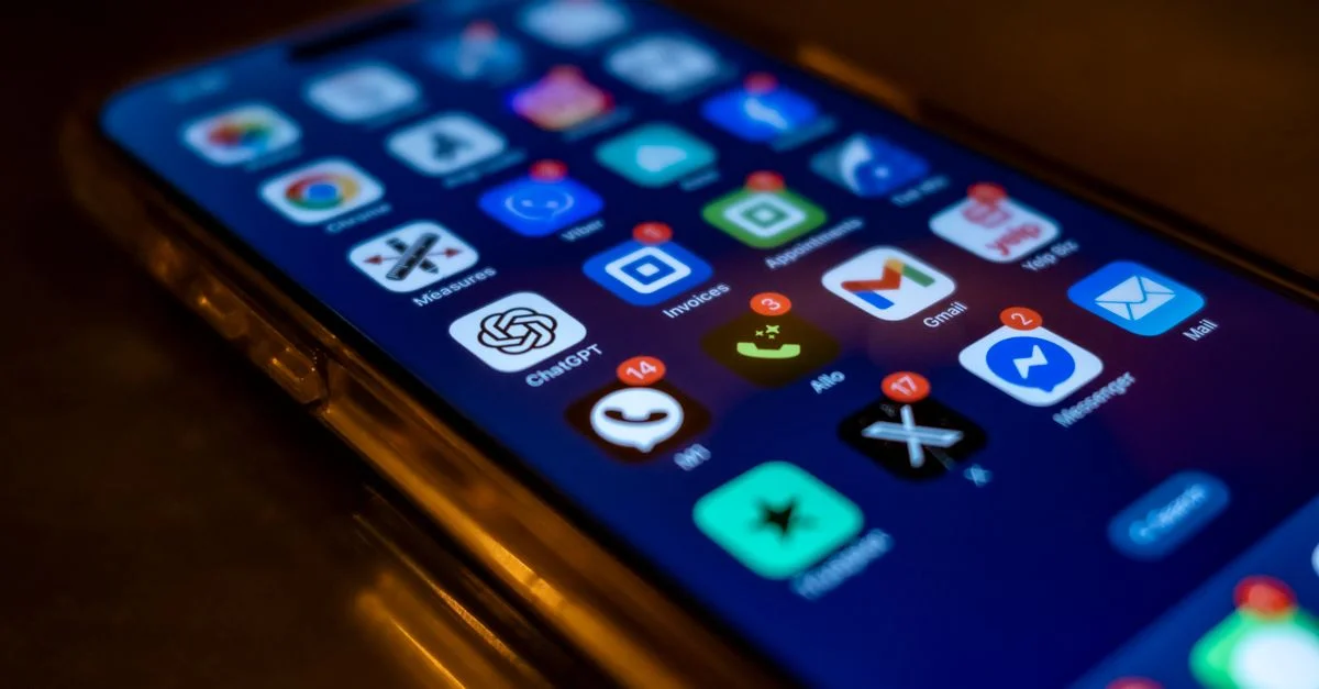Écran de smartphone affichant diverses icônes d'application avec des badges de notification en basse lumière.
