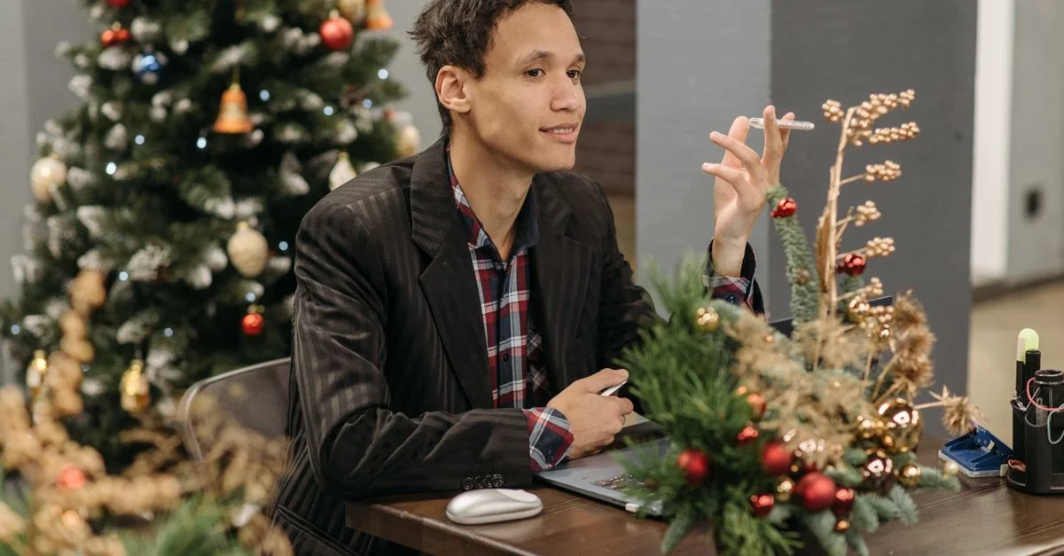 Homme assis à un bureau, entouré de décorations de Noël festives et d'un sapin.