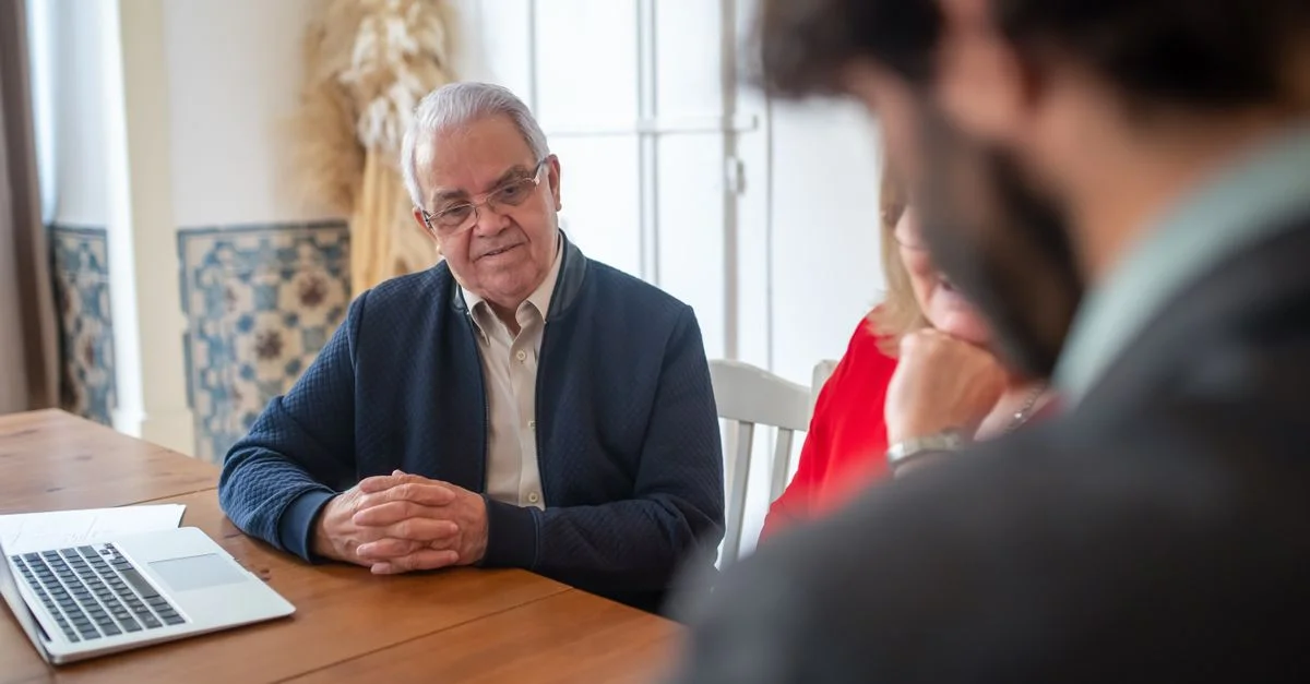 Homme senior interagissant avec des consultants lors d'une réunion d'affaires à l'intérieur.