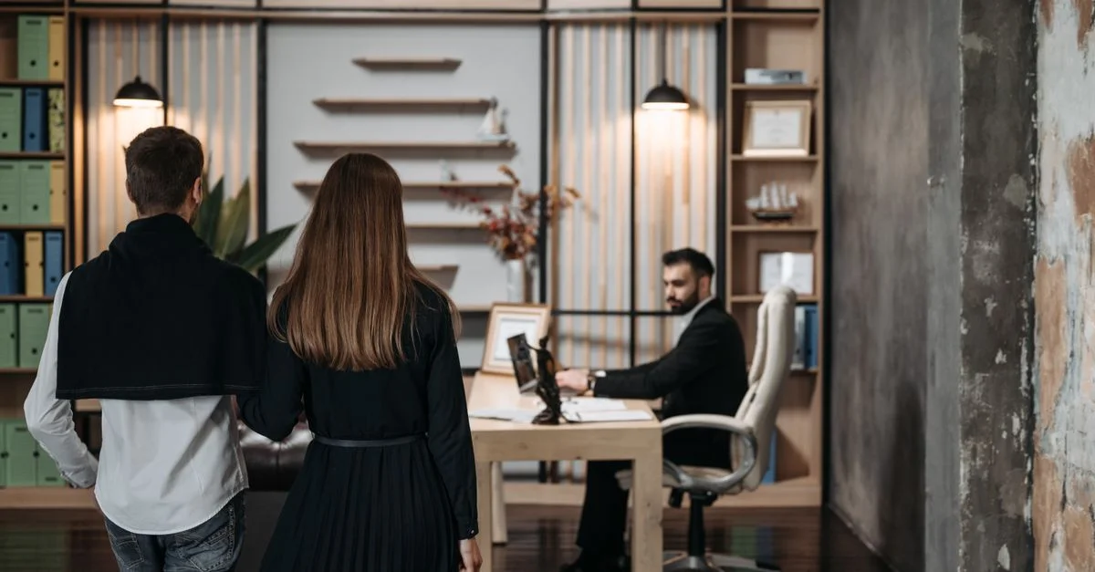 Un couple s'approche d'un avocat dans un cadre de bureau contemporain pour une consultation professionnelle.