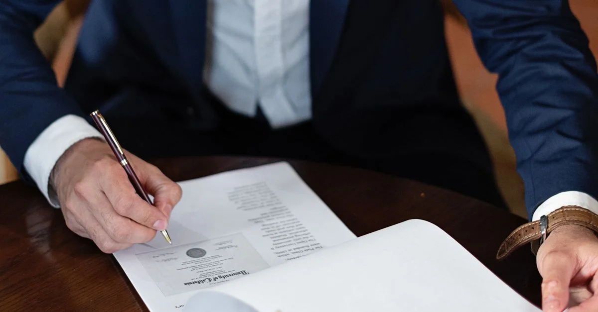 Un professionnel signe des documents légaux à un bureau dans un cadre de bureau.