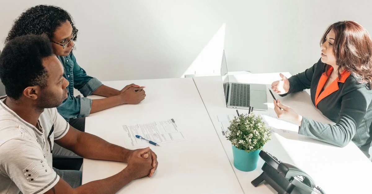 Deux adultes consultant un conseiller juridique dans un cadre de bureau moderne.