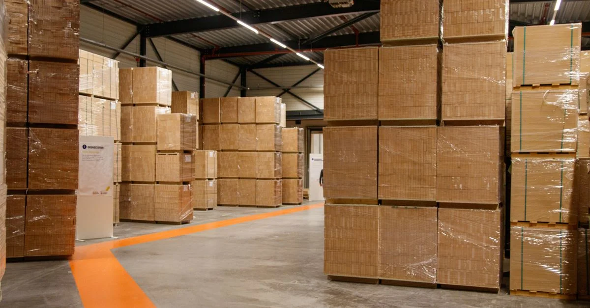Un entrepôt industriel spacieux rempli de boîtes en carton empilées pour le stockage et l'expédition.