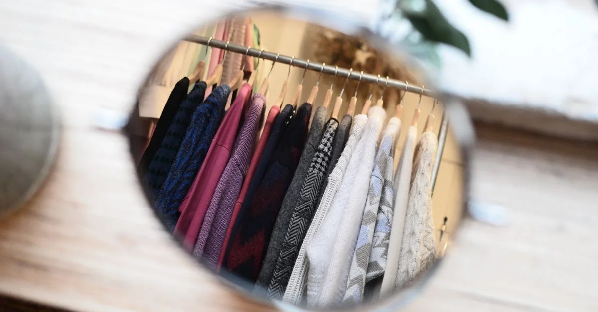 Une prise de vue artistique de vêtements reflétés dans un miroir, mettant en avant un agencement de garde-robe élégant.