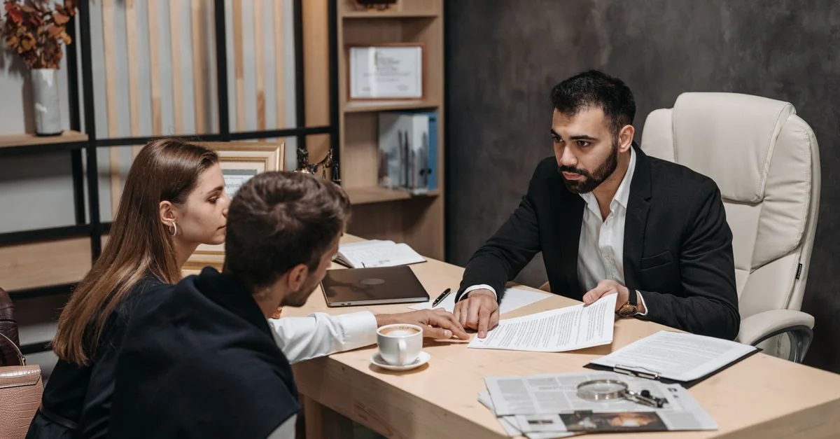Avocat discutant de documents juridiques avec des clients à un bureau.