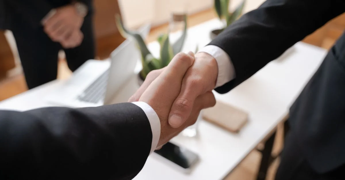 Gros plan sur une poignée de main entre deux professionnels dans un cadre d'affaires, symbolisant un accord.