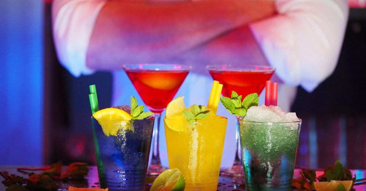 Des cocktails colorés avec des tranches d'agrumes sur un bar, parfaits pour des ambiances nocturnes.