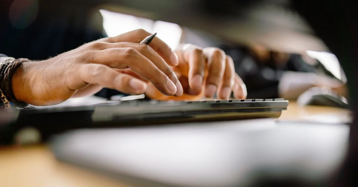 Une vue détaillée d'une personne tapant sur un clavier, mettant en avant la productivité et le travail de bureau.