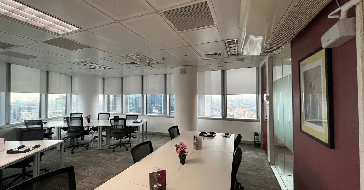 Un intérieur de bureau lumineux et spacieux avec des tables de conférence et une vue sur la ville à travers de grandes fenêtres.