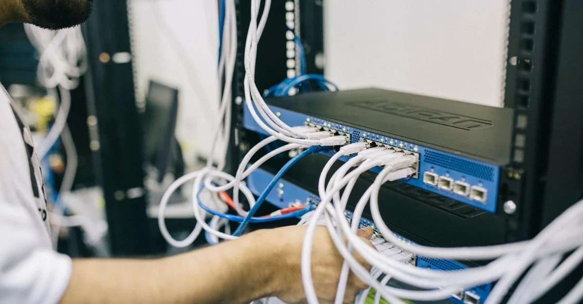 Un professionnel informatique configurant des câbles réseau dans un rack serveur, se concentrant sur les connexions Ethernet.