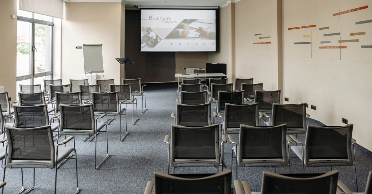 Salle de conférence vide avec des chaises et un écran de présentation aménagés pour des réunions d'affaires.