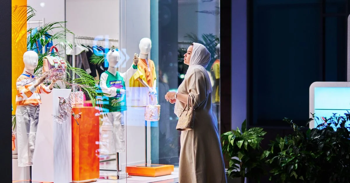 Une femme portant le hijab fait du lèche-vitrines de nuit devant une vitrine éclairée à Istanbul, en Turquie.