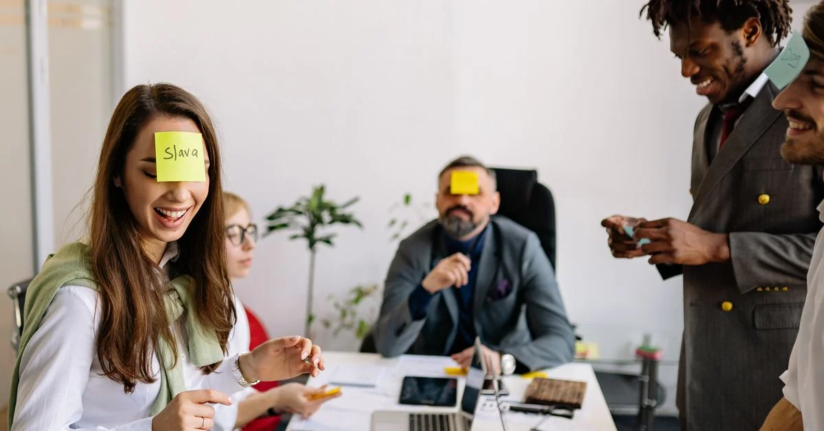 Des collègues de travail divers s'engagent de manière ludique dans un jeu de team-building avec des Post-it dans un bureau.