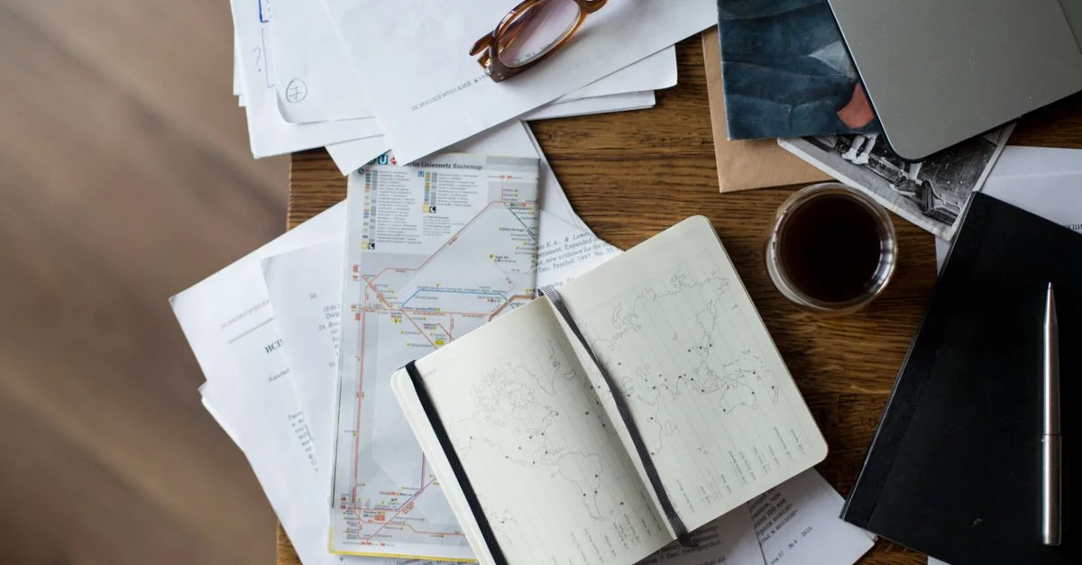 Plan en hauteur d'un espace de travail avec café, cartes, ordinateur portable et documents sur un bureau en bois.