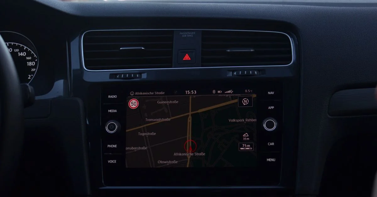 Vue intérieure d'un tableau de bord de voiture montrant un écran de navigation GPS dans un trafic urbain.