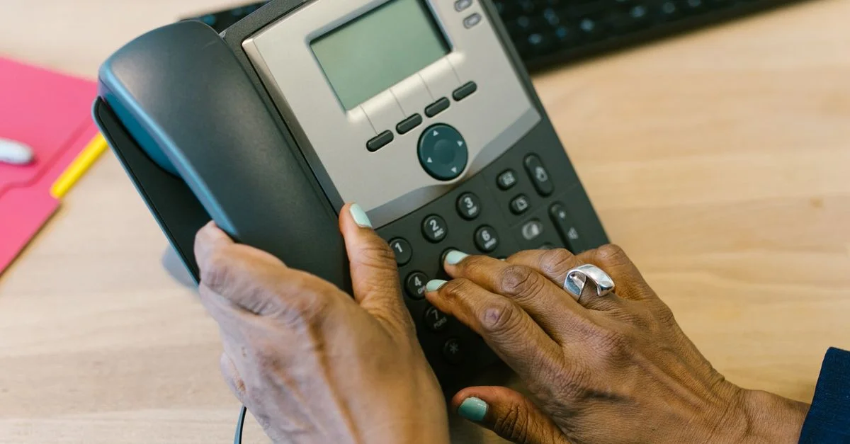 Gros plan sur des mains composant un téléphone de bureau dans un bureau.