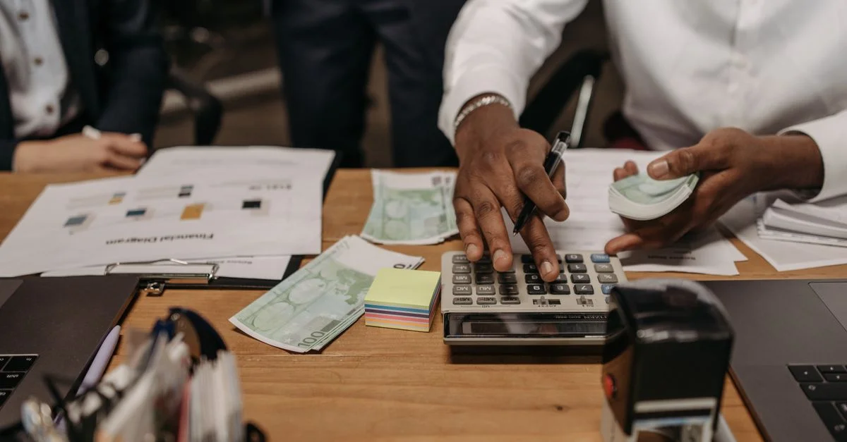 Contexte professionnel avec des personnes manipulant de l'argent et effectuant des calculs avec une calculatrice à un bureau.