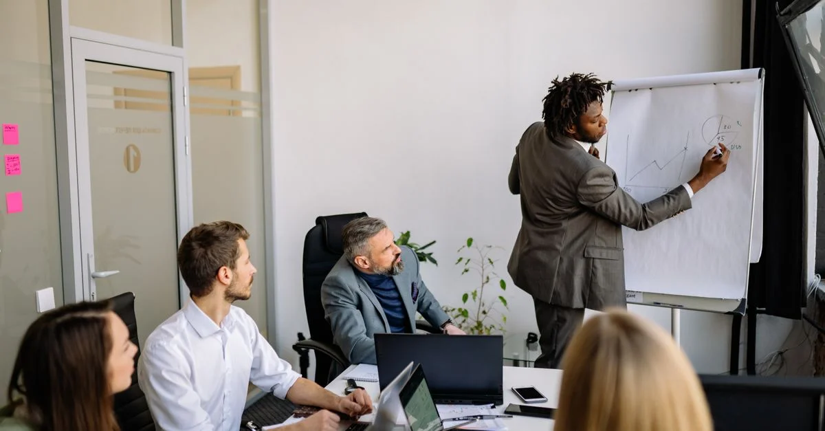 Une équipe diversifiée dans un bureau moderne engagée dans une réunion stratégique dirigée par un présentateur.