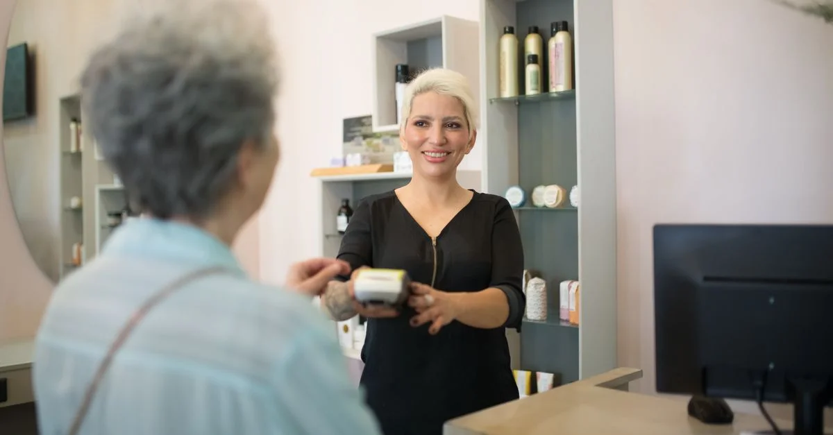 Coiffeur amical aidant un client avec le paiement dans un salon élégant.