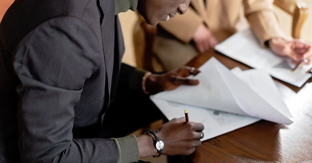 Homme afro-américain concentré sur la signature de documents d'affaires importants à un bureau.