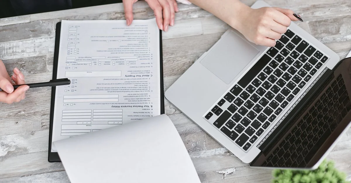 Deux personnes collaborant sur des documents et un ordinateur portable dans un bureau moderne.