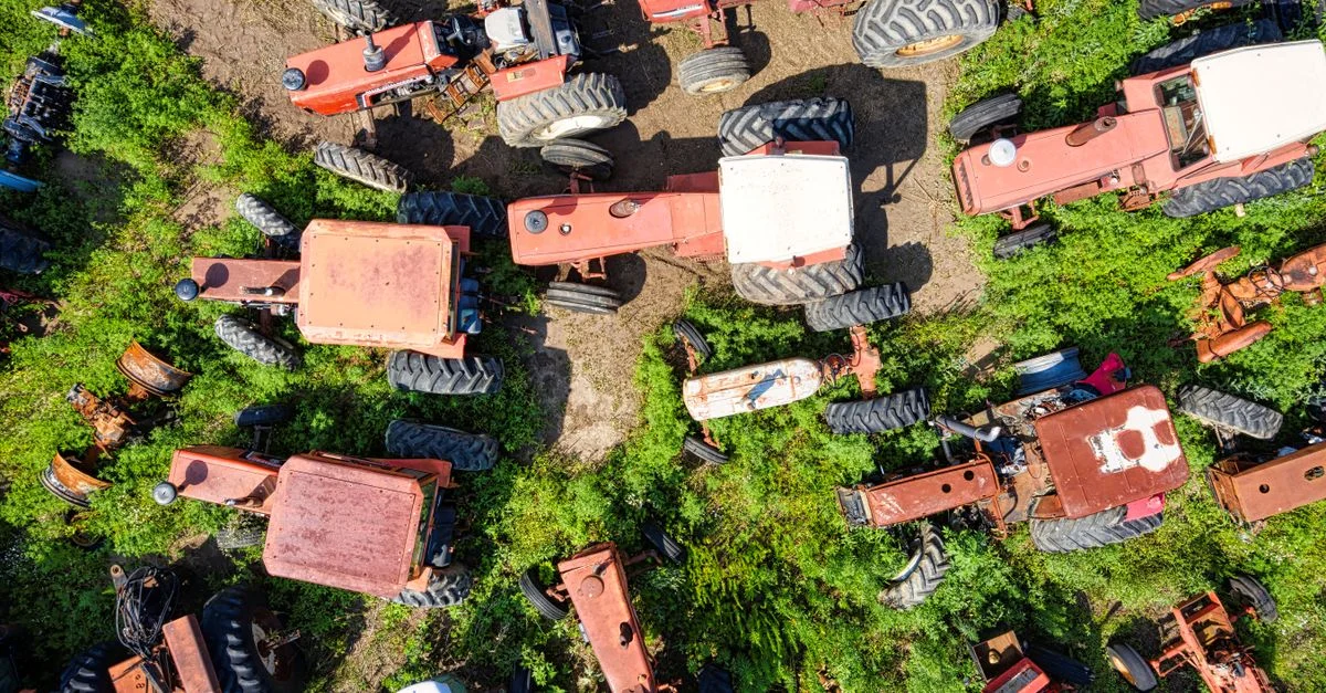 Vue aérienne de tracteurs vintage dispersés dans un champ rural verdoyant du Wisconsin.