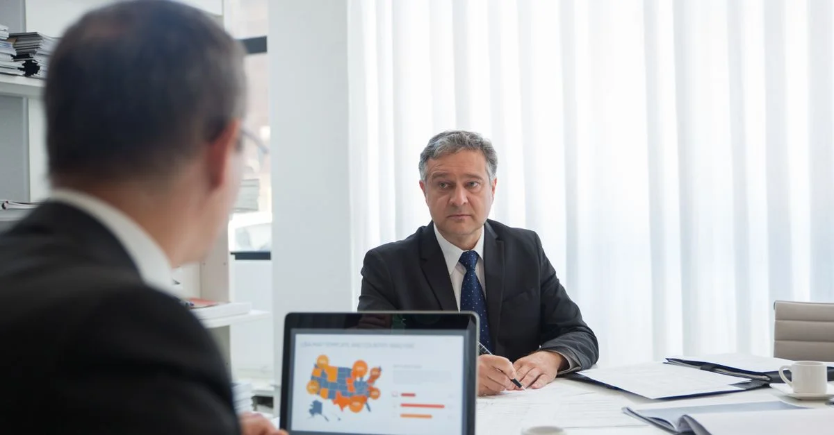 Deux hommes d'affaires en discussion à un bureau avec un ordinateur portable.