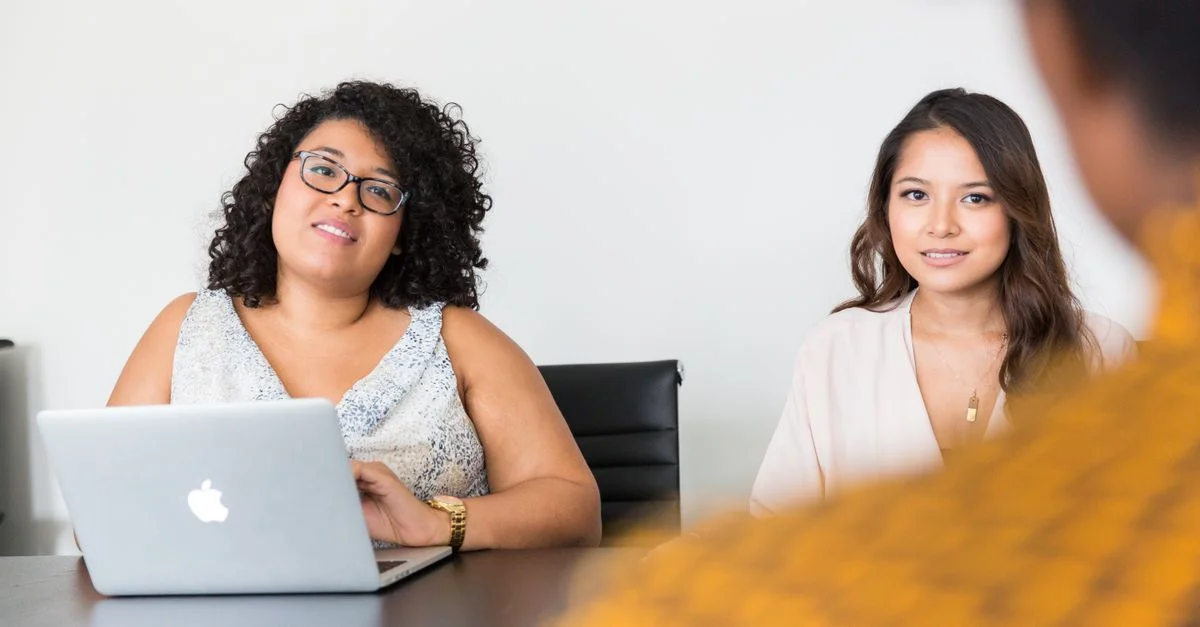 Femmes diverses participant à une réunion d'affaires avec un ordinateur portable, illustrant le travail d'équipe et la collaboration.
