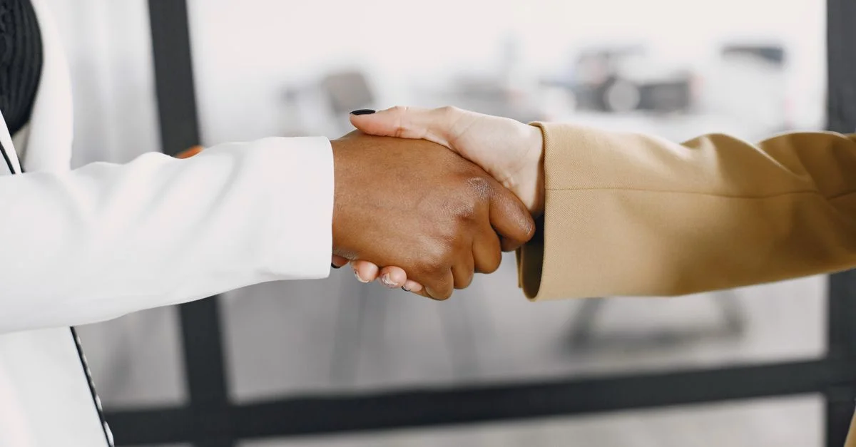 Gros plan sur une poignée de main entre des professionnels de divers horizons en intérieur.