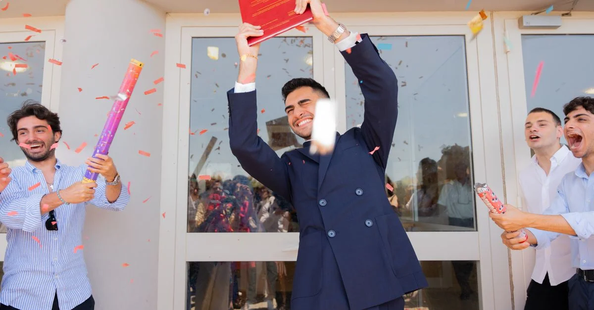Un diplômé en liesse célèbre son succès avec ses amis au milieu des confettis en plein air.