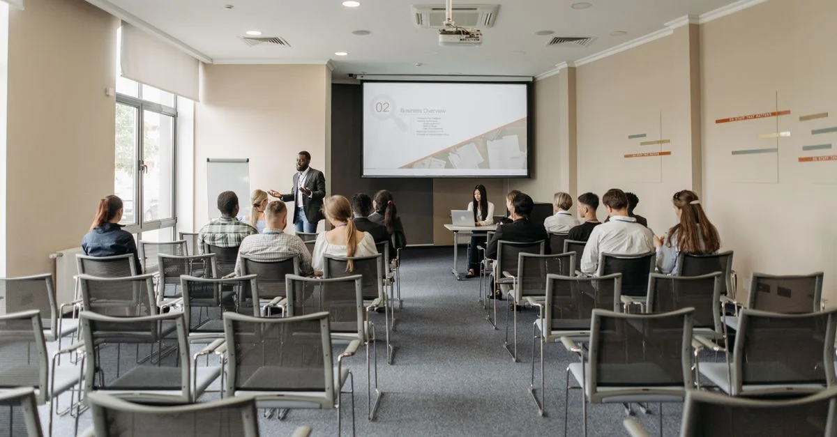 Un groupe assistant à une présentation professionnelle dans une salle de conférence moderne avec projecteur.