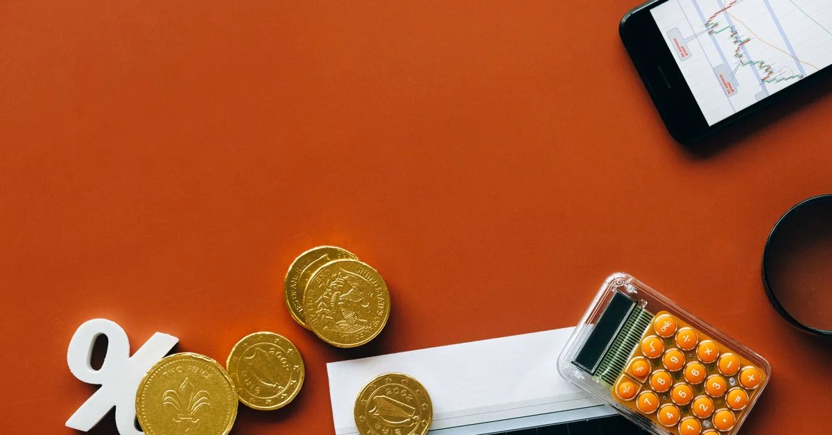 Vue de dessus montrant des pièces, une calculatrice et des graphiques sur un fond rouge pour l'analyse financière et les concepts d'affaires.