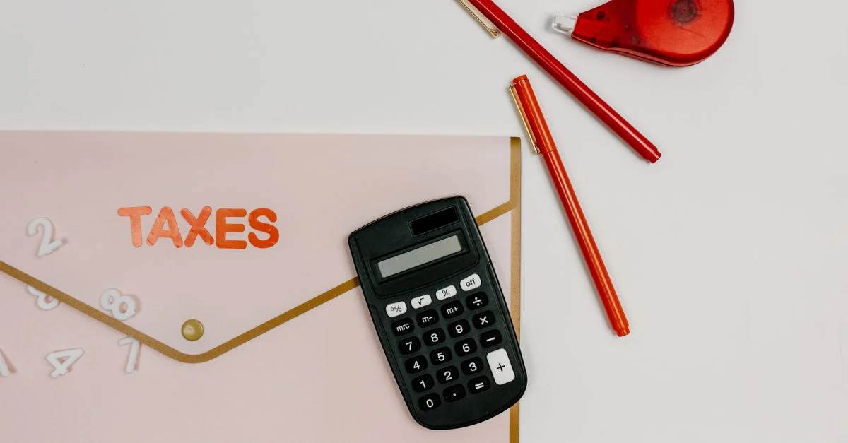 Image en vue de dessus présentant une calculatrice, des stylos et un dossier étiqueté 'IMPÔTS', parfait pour des thèmes financiers.
