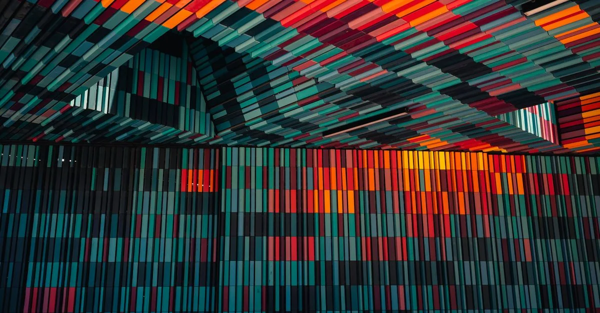 Une arrangement abstrait et vibrant de motifs géométriques colorés sur un mur et un plafond à l'intérieur.