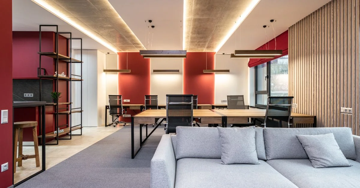 Bureau moderne spacieux avec des murs d'accent rouges, des meubles élégants et beaucoup de lumière naturelle.