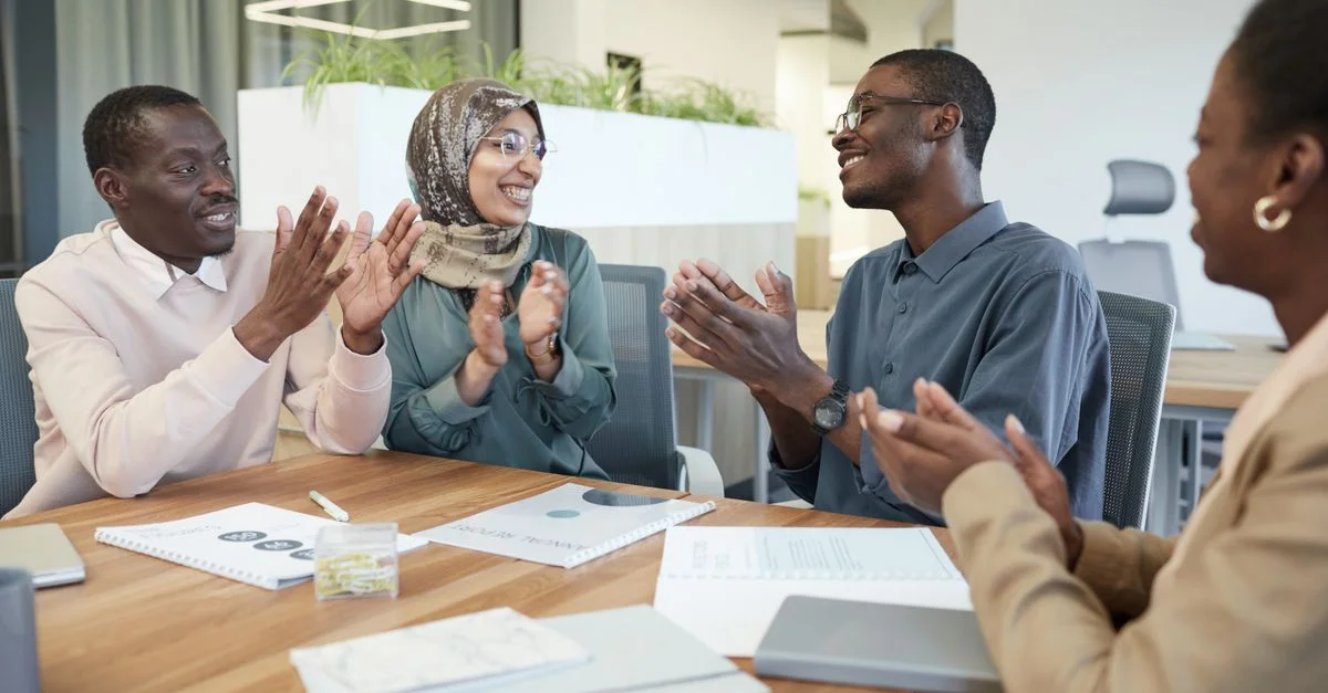 Un groupe multiculturel de professionnels participe à une réunion de bureau positive montrant le travail d'équipe et le soutien.