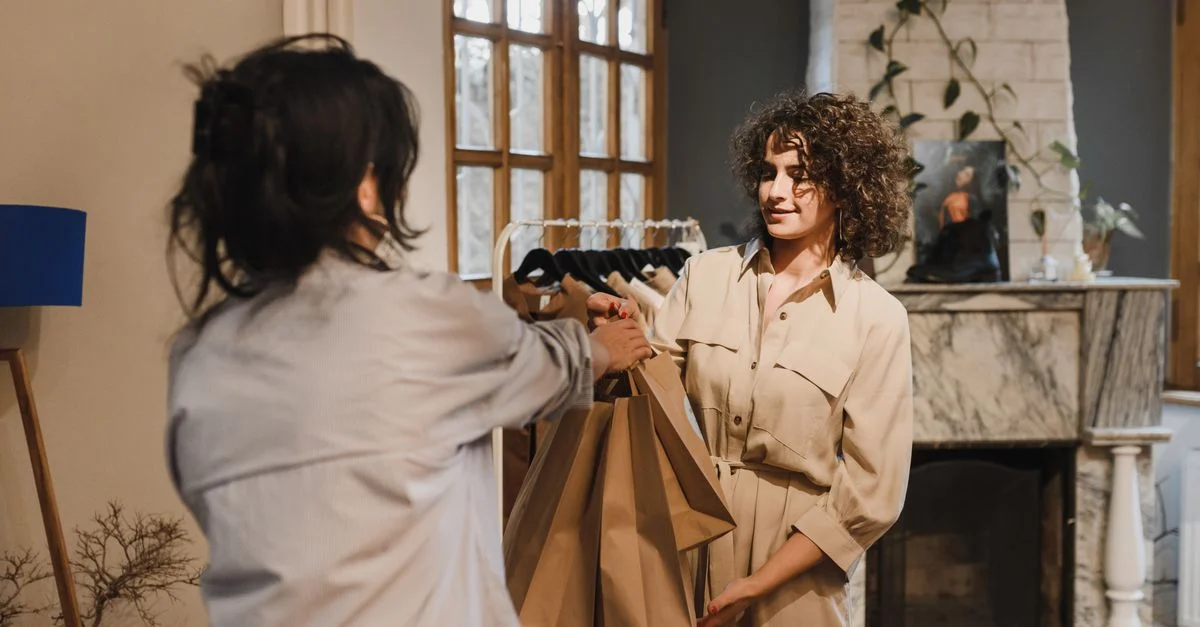 Deux femmes dans une boutique échangeant des sacs de shopping dans un intérieur cosy.