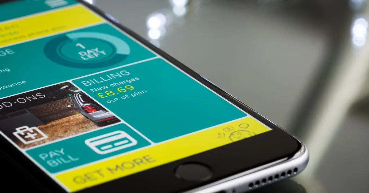 Gros plan d'un smartphone affichant une interface d'application de facturation sur une surface réfléchissante.