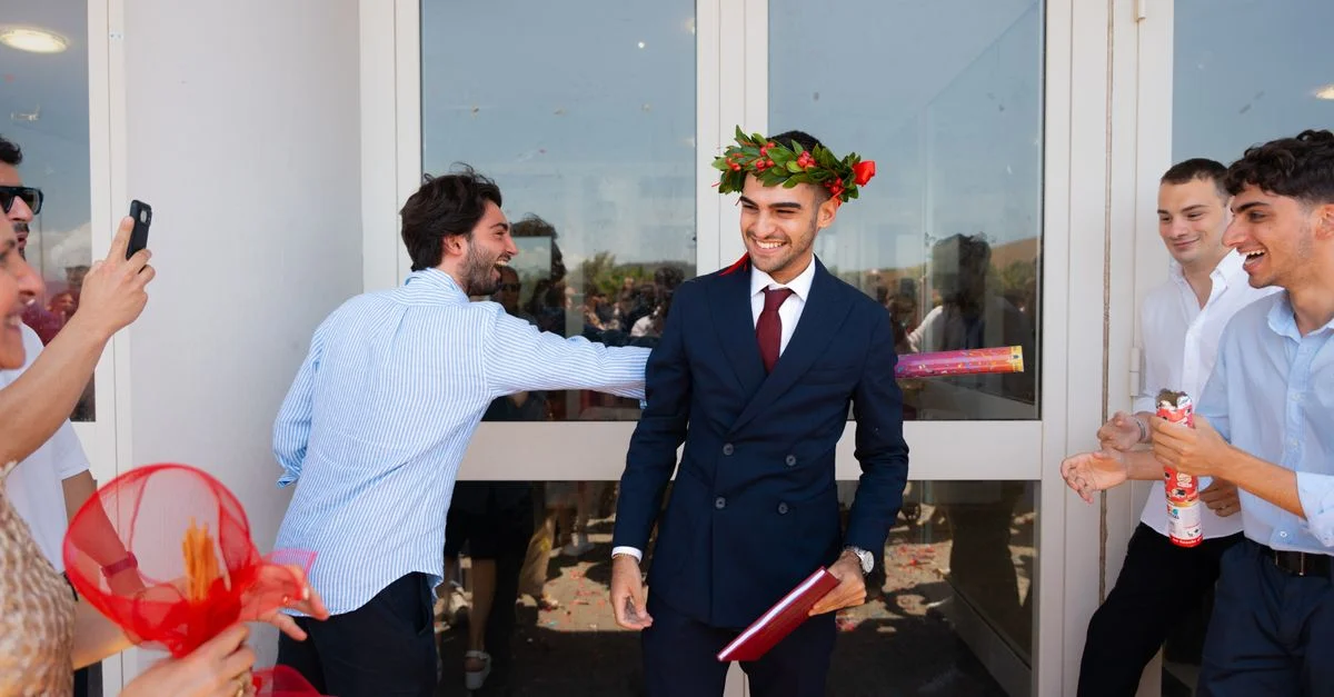 Diplômé joyeux célébrant avec des amis en plein air, portant une couronne de lauriers.