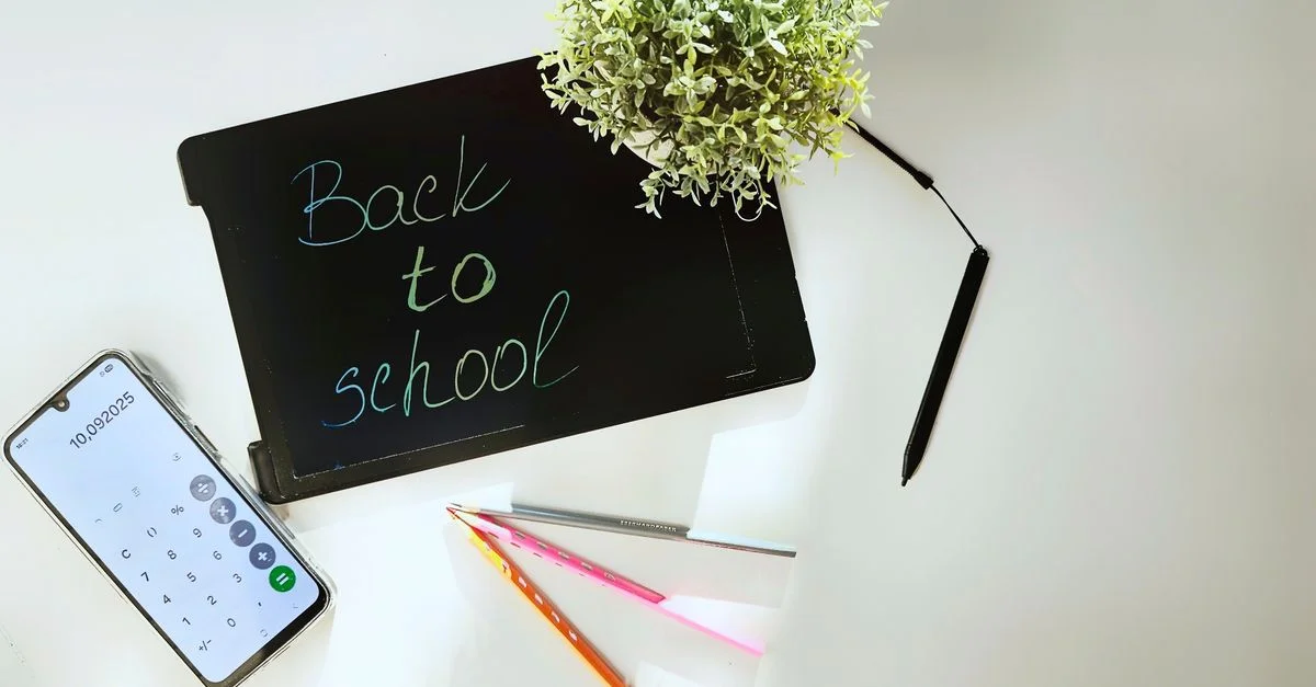 Mise à plat d'un espace de travail de rentrée scolaire comprenant une tablette, un smartphone, des stylos et une plante.