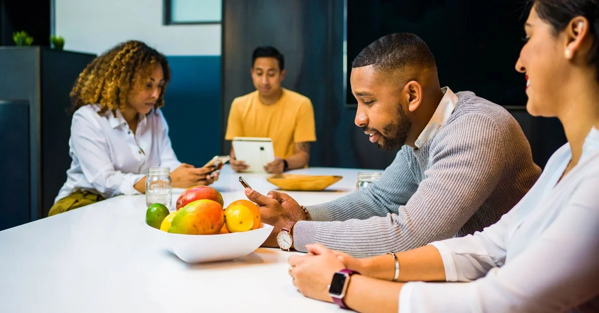 Une équipe diversifiée d'adultes utilisant la technologie tout en faisant du brainstorming dans un environnement de bureau contemporain.