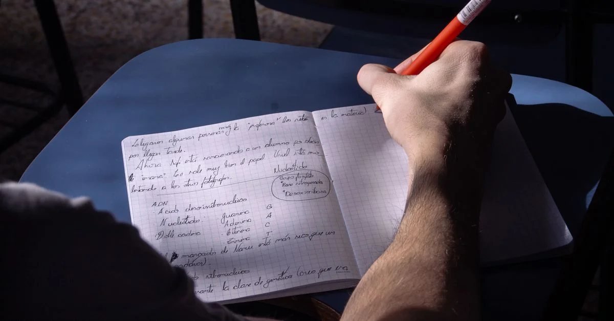 Une étudiante prend des notes dans une salle de classe à Buenos Aires. La lumière naturelle met en valeur le processus d'écriture.