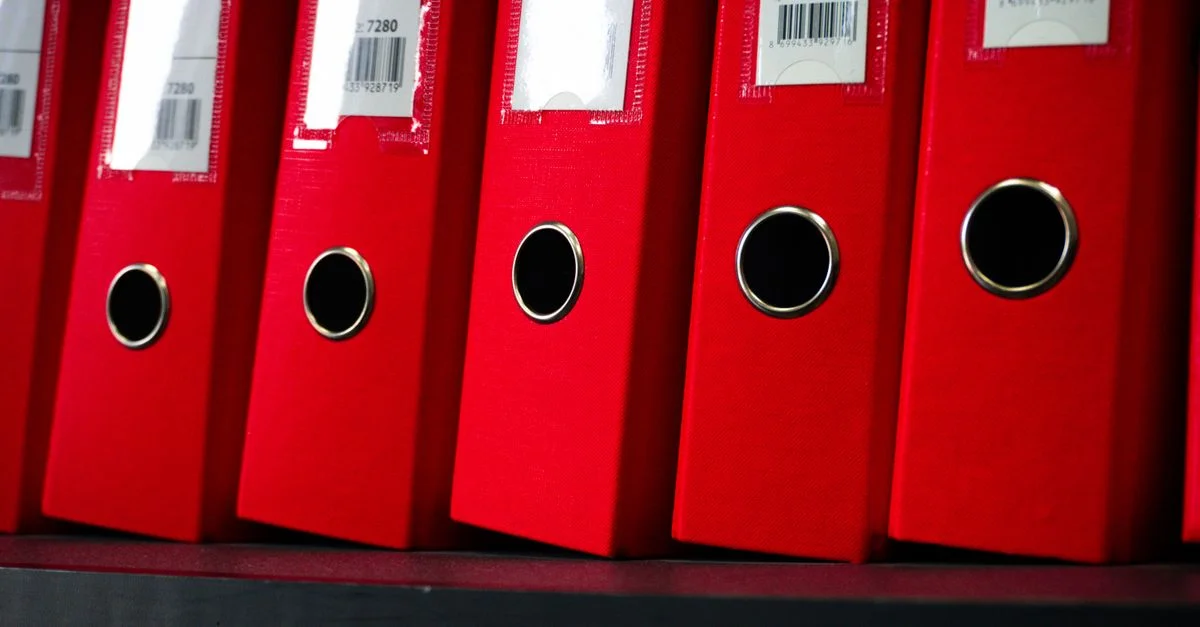 Vue en gros plan de dossiers de bureau rouges soigneusement organisés sur une étagère.