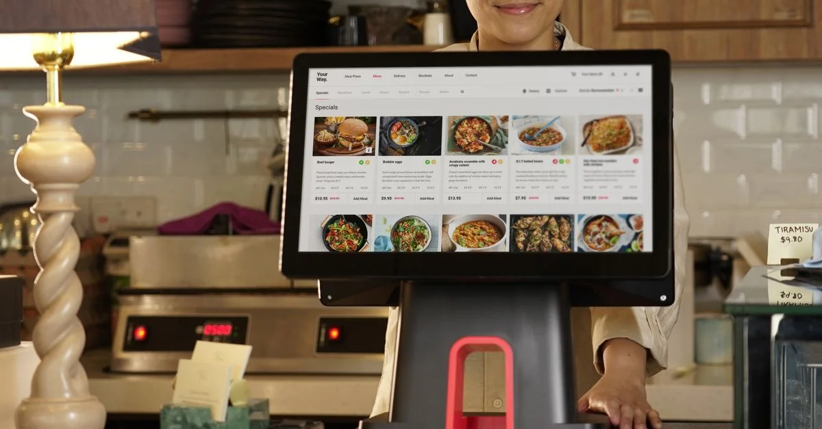 Un caissier utilise un système à écran tactile pour prendre des commandes dans un cadre de restaurant.