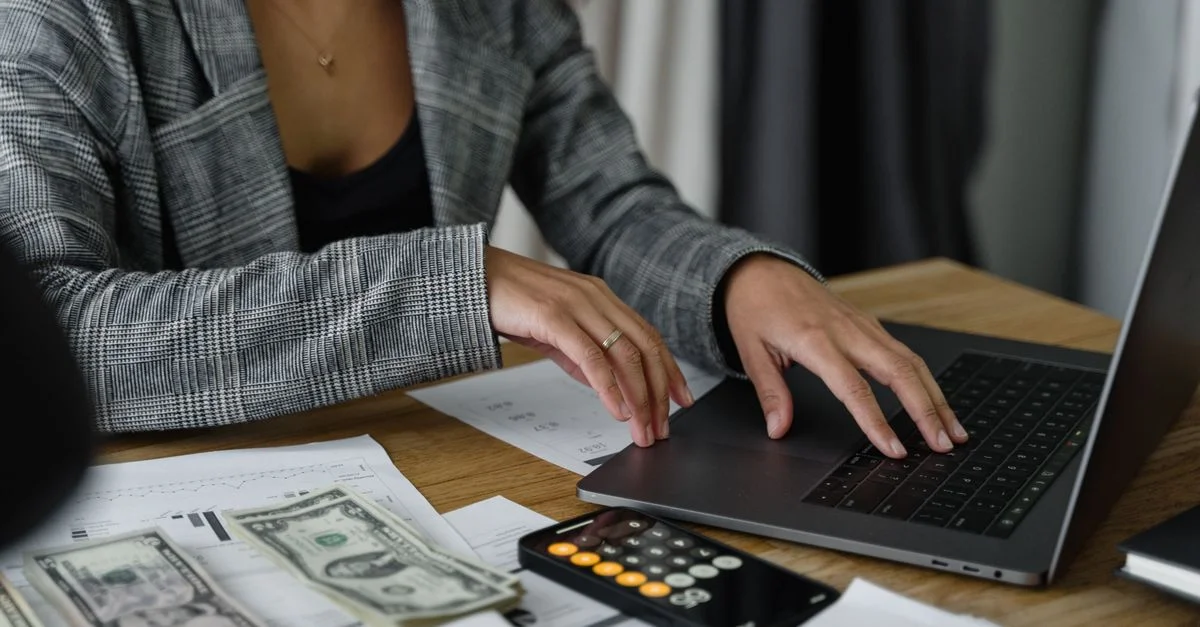 Une femme d'affaires travaillant sur la gestion financière avec de l'argent et une calculatrice sur le bureau.