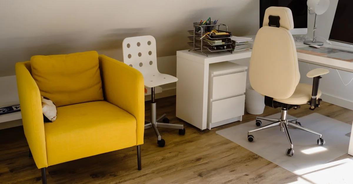 Bureau à domicile lumineux avec une chaise jaune et un espace de travail bien organisé.